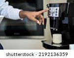 Male hand using modern coffee machine in the morning making coffee at home or in office. Business man or barista brewing espresso coffee beverage in cup using coffeemaker. Close up view