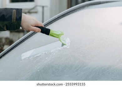 male hand using a scraper to remove ice and frost from a car window on a winter day. Concept of winter car care, car accessories and preparation for the cold season. - Powered by Shutterstock - Get 15% off with code: PIKWIZARD15