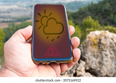 Male Hand Using A Smartphone With A Rain Alert Application, With A Natural Background.