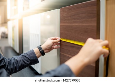 Male hand using tape measure on cabinet panel choosing materials or countertops for built-in furniture design. Shopping furniture and house decoration. Home improvement concept