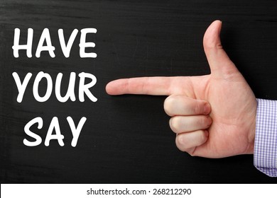 Male Hand Wearing A Business Shirt Pointing At The Phrase Have Your Say In White Text On A Blackboard