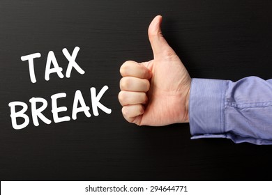 Male Hand Wearing A Business Shirt Giving The Thumbs Up Sign For The Phrase Tax Break In White Text On A Blackboard