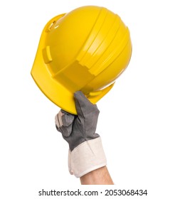 Male hand wearing working glove holding yellow hard hat. Close up of gloved hand of repairman with construction helmet, isolated on white background.