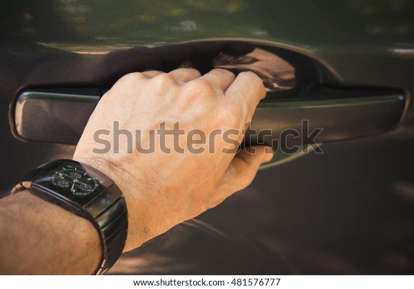 Male hand with wirst watch opens car door, closeup\
photo with selective focus