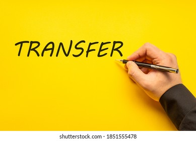 Male hand writes in black pen the word transfer on a yellow background with copy space. Business concept photo