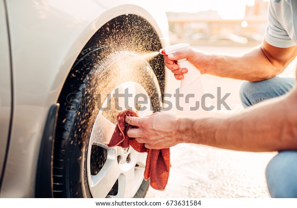Male hands cleans\
disk with car rim cleaner