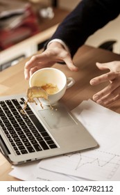 The male hands and coffee in white cup spilling in slow motion or movement on the table with laptop and documentation in the morning working day. The danger, security, safety, safeness, protection