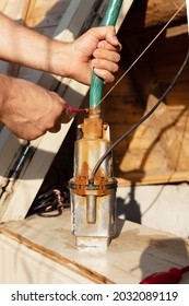 Male Hands Connect An Old Rusty Well Pump With A Hose Using Hose Clamp And Tighten The Screw With A Screwdriver. Pump Repair