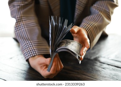 Male hands counting American one hundred dollar bills against the background of smaller bills of money lying on the table - Shutterstock ID 2313339263