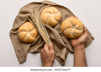 Male hands with delicious kaiser rolls and wheat ears on napkin against white background - Powered by Shutterstock