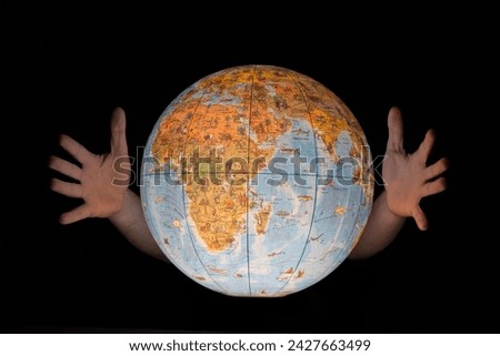 Male hands engulfing a glowing earth globe, isolated on black