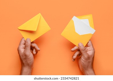 Male hands with envelopes and blank card on color background, closeup