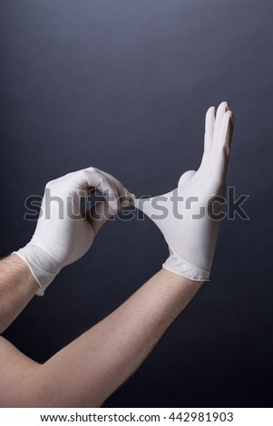 Male hands in golves. Doctor or nurse putting on latex gloves. Sanitary, healthcare, medical clothing. Dark background