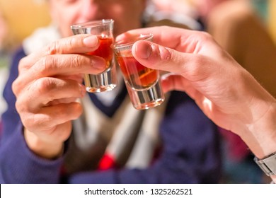 male hands having toast with shot glasses of grappa