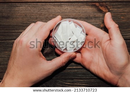 Male hands hold in hand a box of snus with nicotine spiders.