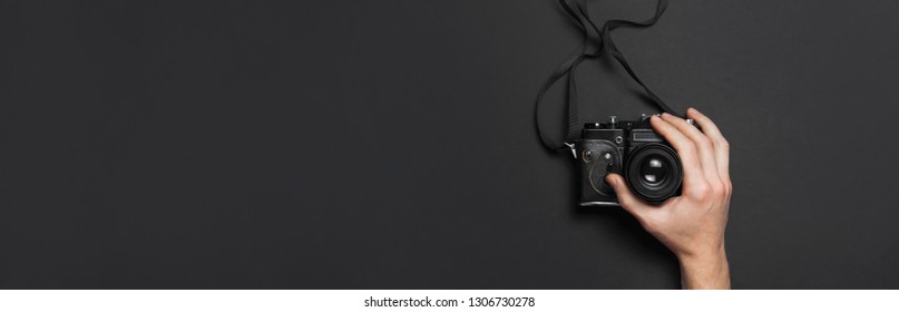 Male hands hold old vintage camera on black background top view flat lay with copy space. Concept for the photographer, old photographic equipment, minimalistic style long banner - Powered by Shutterstock