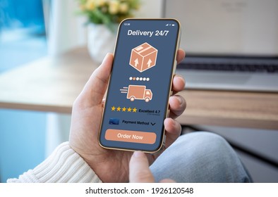 Male Hands Hold Phone With Parcel Delivery Application On Screen Against Background Of Room In House 
