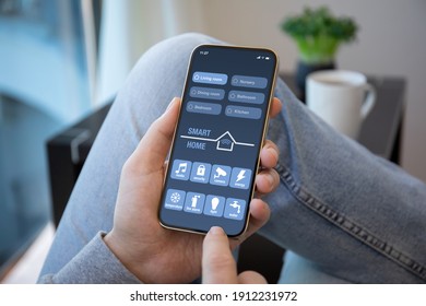 Händchen halten Handy mit Smarthome-Anwendung auf dem Bildschirm im Zimmerhaus 