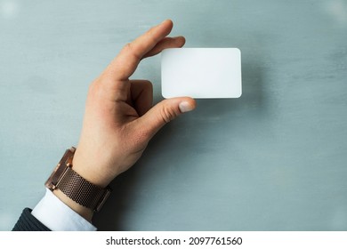 Male hands holding a blank card on a gray background. - Shutterstock ID 2097761560