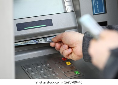Male hands holding bunch of hundred dollars banknotes at atm machine closeup