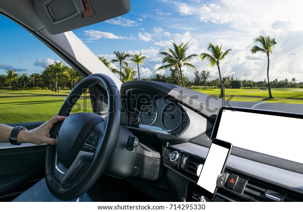 Male hands holding car steering wheel. Hands on\
steering wheel of a car driving. Driving a car inside cabin.\
Multimedia system and smartphone isolated white blank screen. Copy\
space. Space for text.