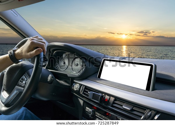 Male hands\
holding car steering wheel. Hands on steering wheel of a car\
driving near the sea. Man driving a car inside cabin. Multimedia\
system isolated white blank screen. Copy\
space