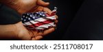 Male hands holding Flag of the United States of America, shape of the USA map. Photo for presidential election 2024, People will decide the future of America. Black edit space, panoramic format