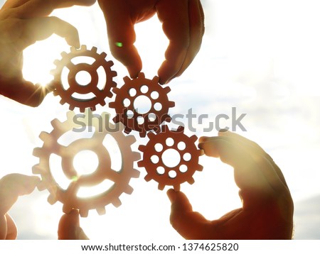 Male hands holding  four 4 wooden cog wheels, gear wheels on  sunny sky background. family concept.