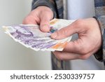 male hands holding money, counting English pound sterling bills, rejoices in success, anticipates what to spend, encouraging good financial behavior, economic awareness