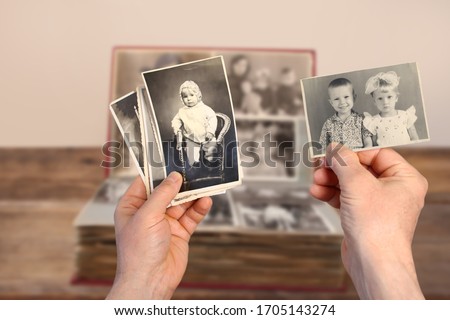 male hands holding an old retro album with vintage monochrome photographs in sepia color 1964-1965, the concept of genialogy, memory of ancestors, family ties, childhood memories