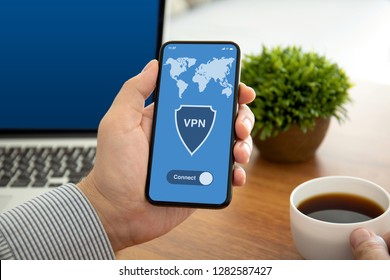 male hands holding phone with app vpn on the screen above the table in the office