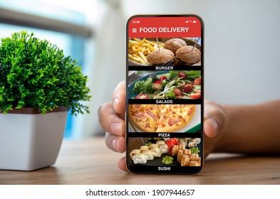 Male Hands Holding Phone With Food Delivery App Over The Table 