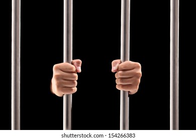 Male hands holding prison bars isolated on black background