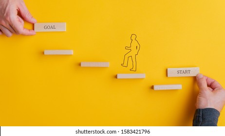 Male Hands Holding A Start And Goal Card At The Beginning And End Of Steps A Silhouette Of A Man Is Climbing. Over Yellow Background.