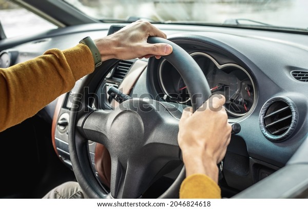 Male hands\
are holding the steering wheel close up. Man in a yellow sweater is\
driving a car. Concept of\
travel.