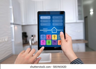 male hands holding tablet with app smart home on background kitchen in house