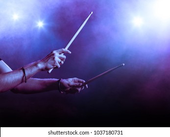 Male hands holding two drum sticks. Smoky backgroung. Backlit