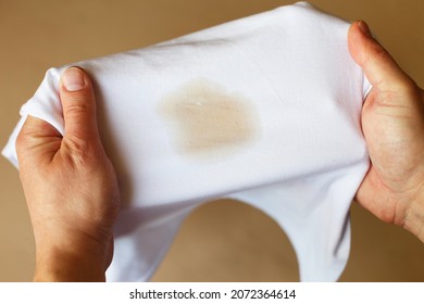 Male Hands Holding A White Shirt With A Dirty Stain From Coffee Or Tea.