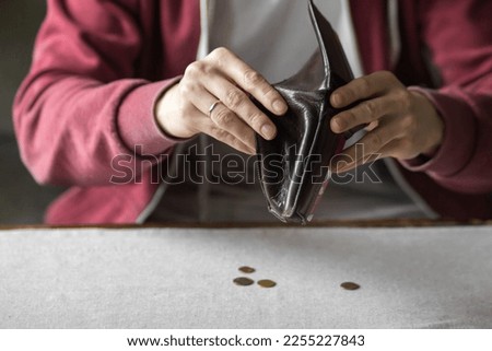 Male hands holds open empty wallet over the table. Young man counting his money in a period of crisis. Poverty concept.