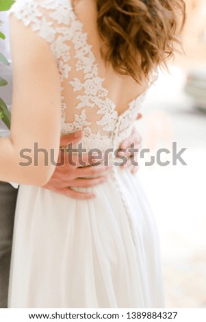 Male hands hugging woman wearing dress. Concept of wedding photo session and tender love.