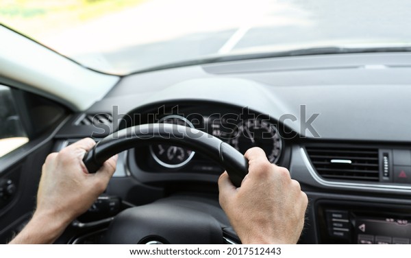 Male hands on the steering wheel of a\
car, inside view. Vehicle management, close-up view of the\
dashboard and interior. The man behind the\
wheel.