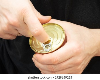 Male hands open a tin can of meat in close-up. Canned food for camp, travel, army, or others.