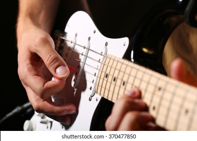 Male hands playing electric guitar with plectrum closeup photo. Learning musical instrument, music shop or school, blues bar or rock cafe, having fun enjoying hobby concept - Powered by Shutterstock