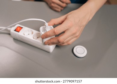 Male hands plugging a smart plug into a power strip and pressing its button, illustrating easy setup, remote control, energy saving home automation in a modern indoor setting.