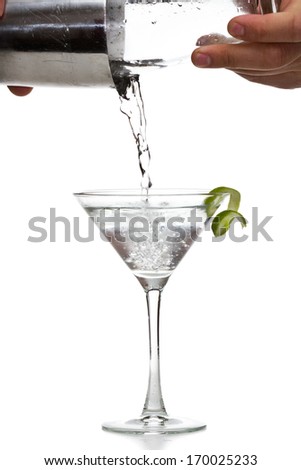 male hands pouring a vodka martini in to a chilled glass with a lime garnish