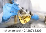 Male hands in protective gloves hold test tube in hands produces chemistry test of motor oil automatic gearbox and hydraulic booster