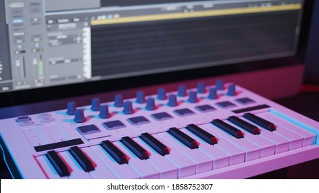 Male Hands Recording Music, Playing Electronic Keyboard, Midi Keys On The Table With Neon Lights. Closeup Of Male Hands Composing Music In Night, Music Sequencer And Midi Controller