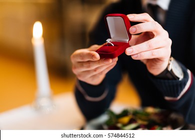 Male hands with red velvet box containing engagement ring with brilliant