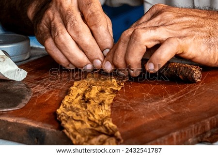 Male hands roll a Cuban corona cigar, encasing a Colorado Claro medium brown wrapper leaf, showcasing the craftsmanship and tradition of homemade cigar-making in Cuba captured in this close-up.