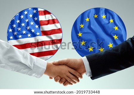 Male hands shaking hands against the background of the flags of America and Europe. The concept of friendship of peoples, contract, cooperation